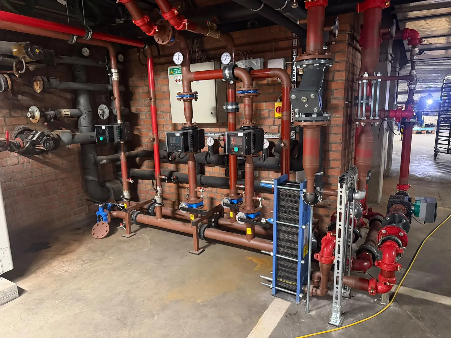 Plant room pipework installation with circulation pumps, plate heat exchanger and flanged valves