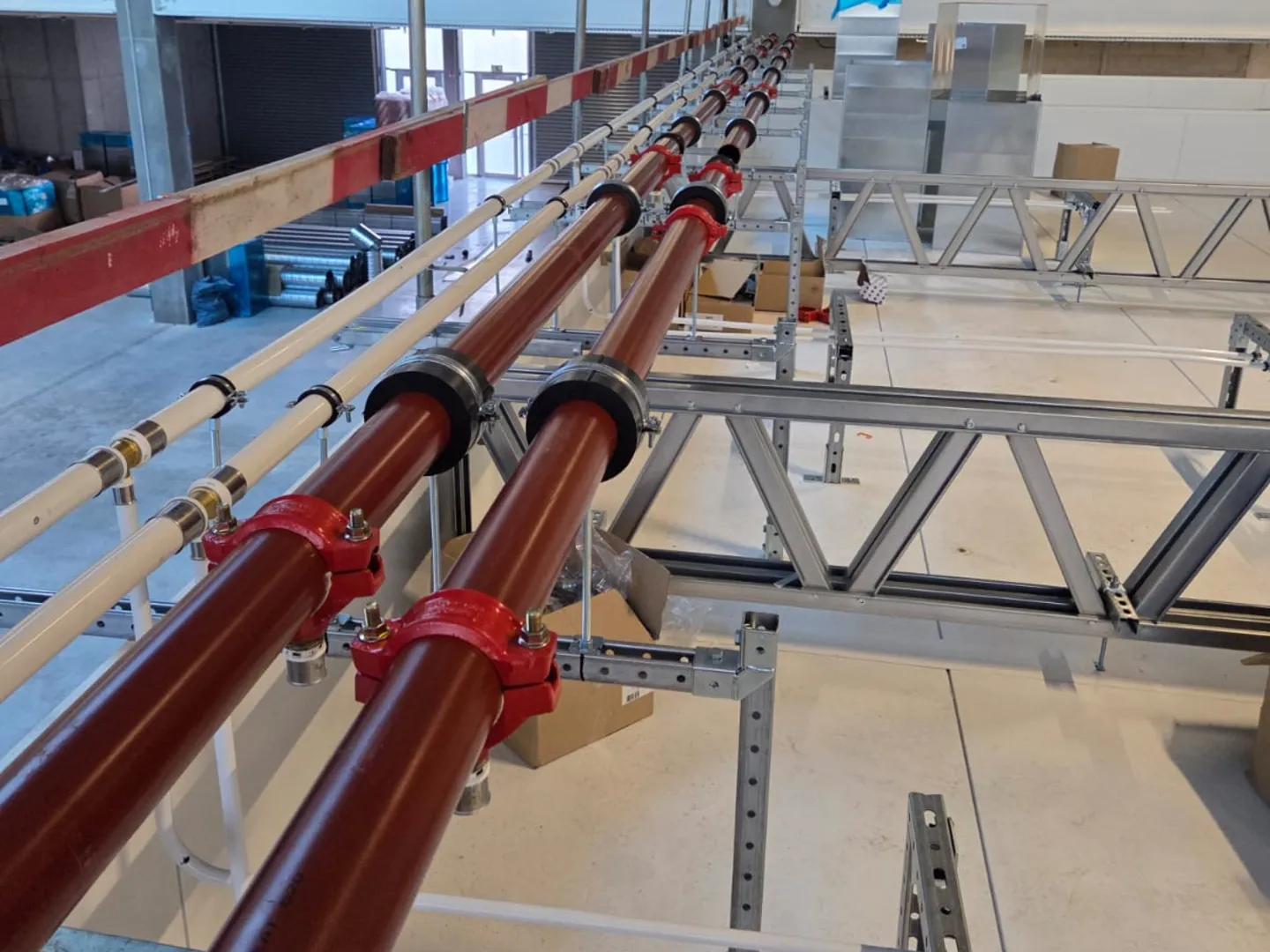 Grooved red-coupled steel pipelines installed on support racks in a new industrial building